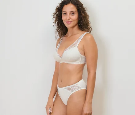 Une femme pose en portant un soutien-gorge et 2 slips crème.