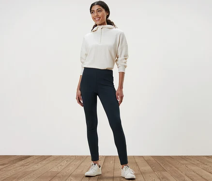 Une femme debout sur un plancher en bois porte un legging heavy et un sweat-shirt.