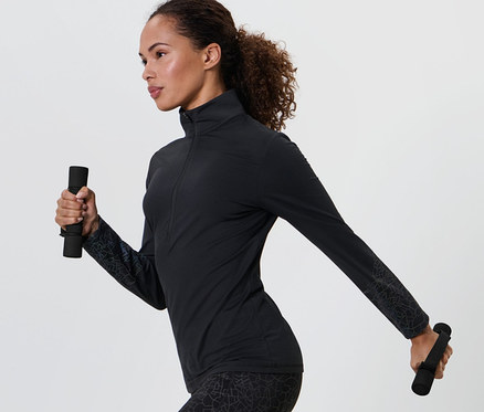 Femme en tenue de sport noire tenant 2 Haltères de course et de gymnastique dans chaque main.