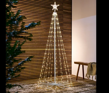 Un arbre à LED pliant se dresse sur un plancher en bois saupoudré de neige.