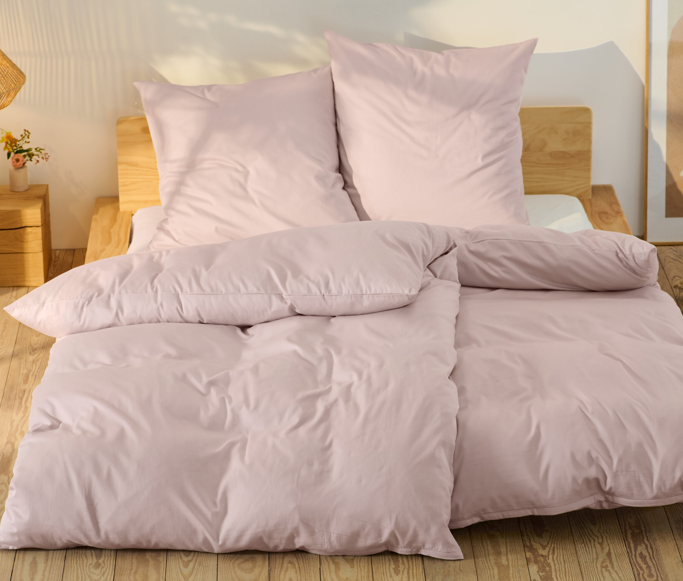 Parure de lit rose en satin de coton de taille standard et grande taille sur un lit.