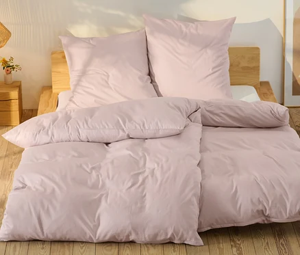 Parure de lit rose en satin de coton de taille standard et grande taille sur un lit.