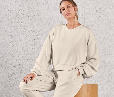 Une femme est assise sur un tabouret en bois et porte un sweat-shirt très doux et un pantalon molletonné très doux.