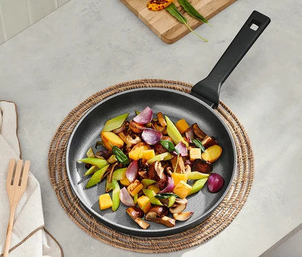 Des légumes sont cuits dans une poêle en aluminium de qualité professionnelle d'environ 28 cm.