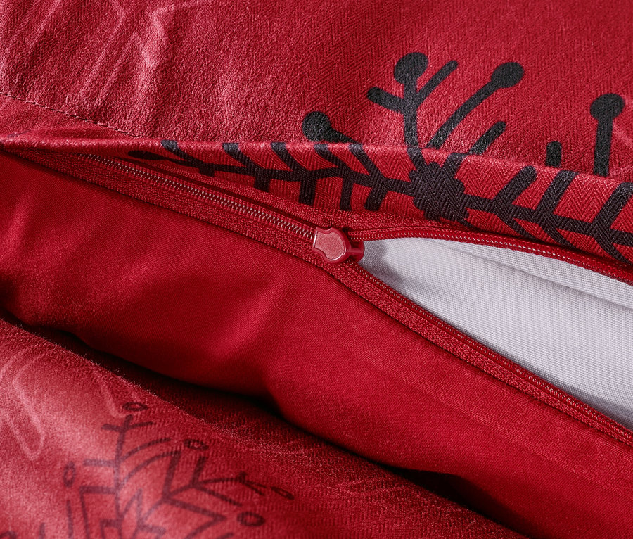 Vue détaillée de la parure de lit rouge en microfibre et flanelle avec fermeture éclair et motifs de flocons de neige noirs.
