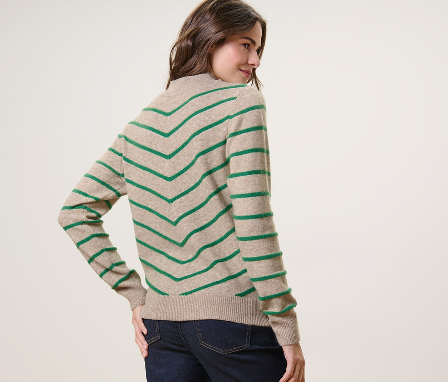Femme regardant par-dessus son épaule et posant dans un pull rayé en maille à col montant, crème.