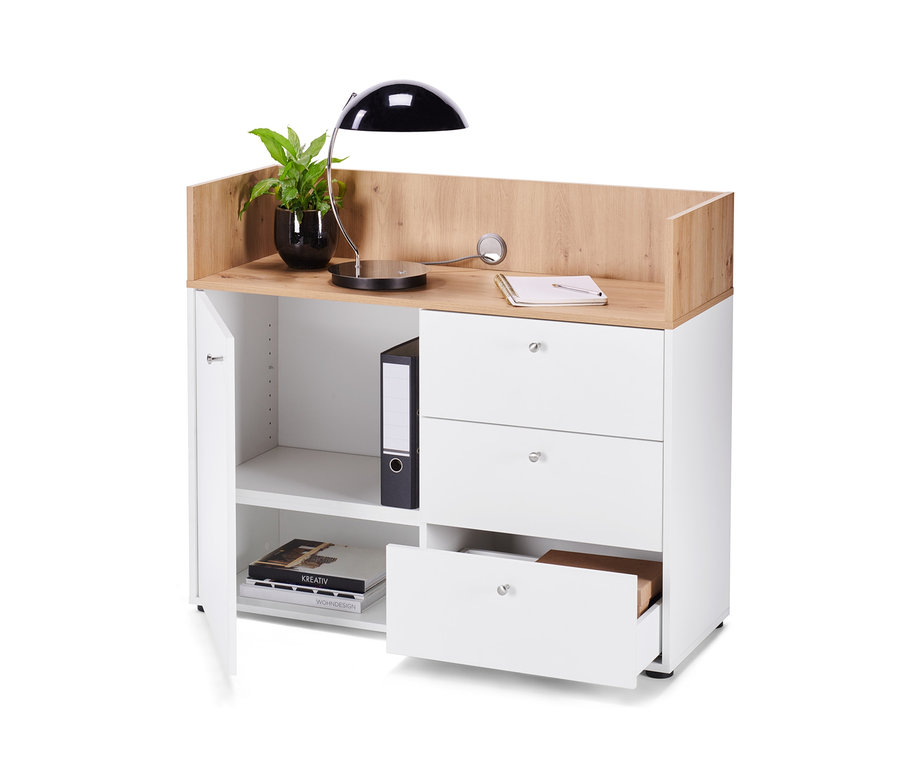 Un buffet avec tiroirs et porte sur lequel reposent une lampe et une plante.