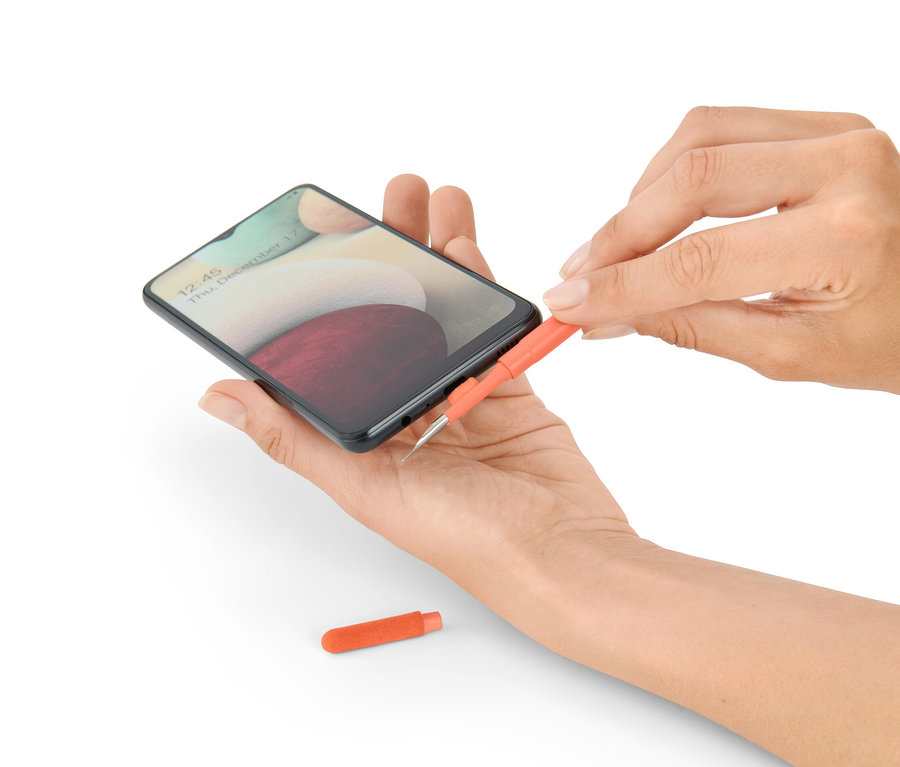 Une femme nettoie un téléphone avec un set de nettoyage de bureau 4 en 1.