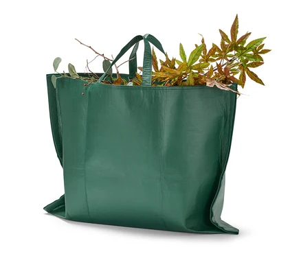 Un sac à déchets de jardin vert rempli de feuilles et de branches.