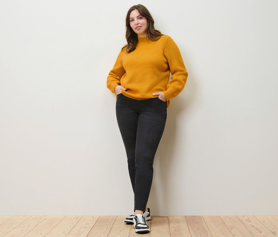 Femme posant en pull en grosse maille et jean slim – Fit « Emma ».