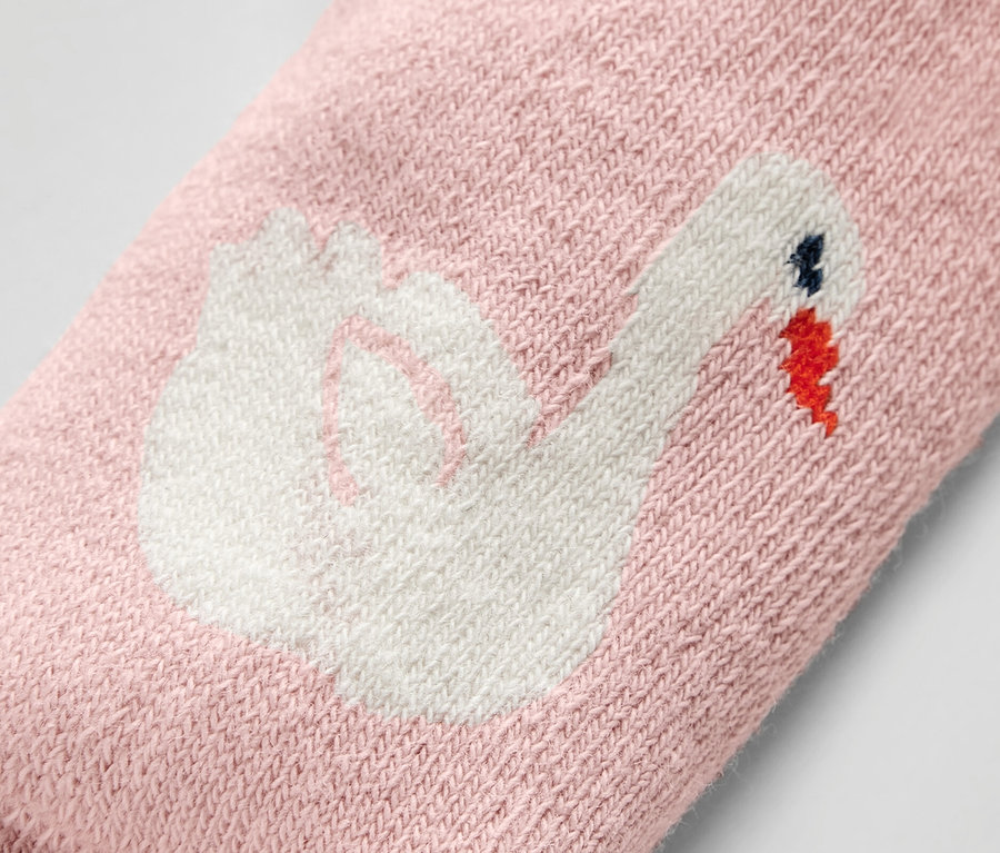 Gros plan d'une chaussette rose pour bébé ornée d'un cygne.