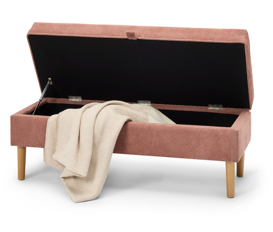 Banc de rangement rose ouvert avec une couverture beige à l'intérieur.