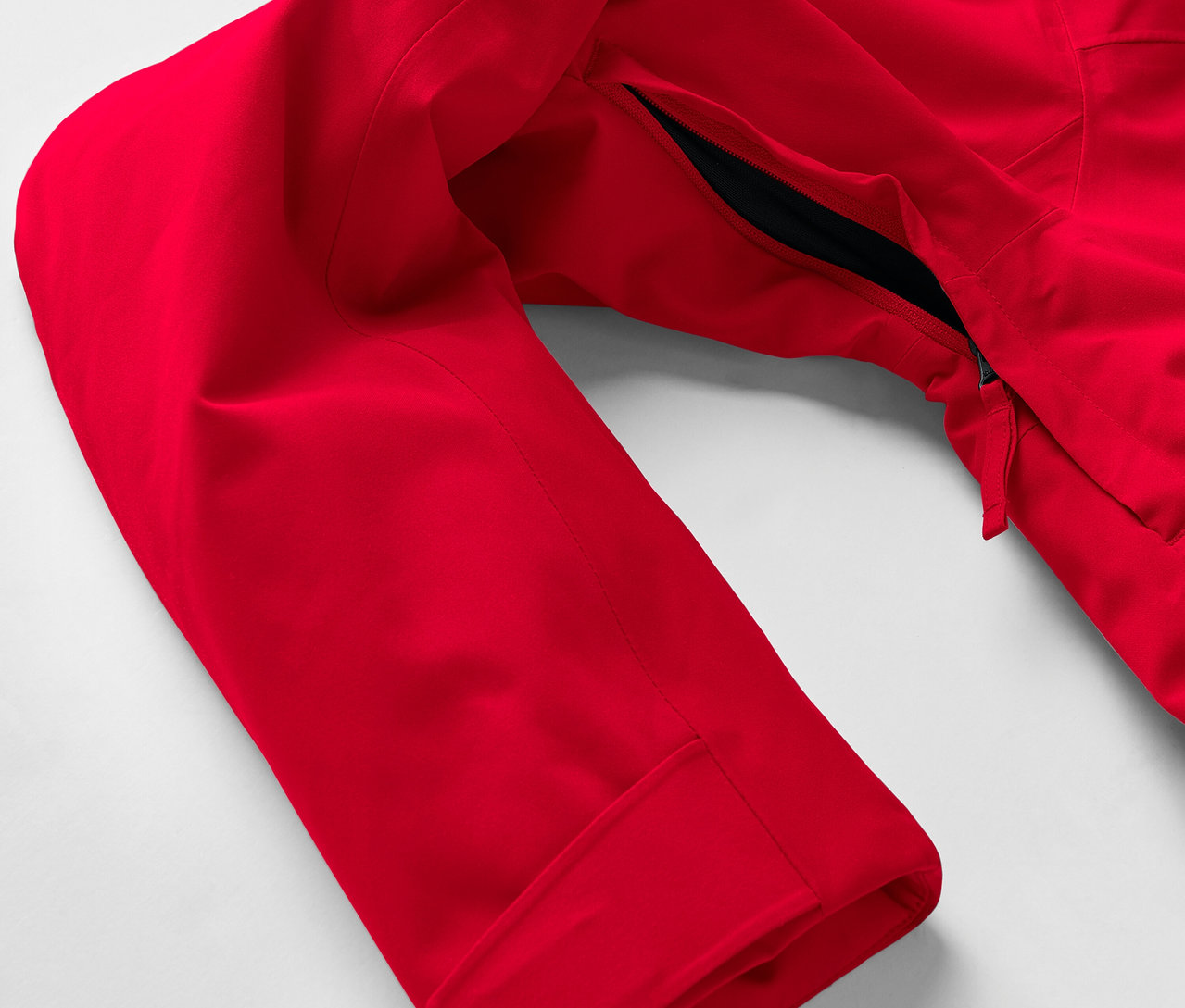 Détail d'une veste rouge avec une manche et une poche zippée.