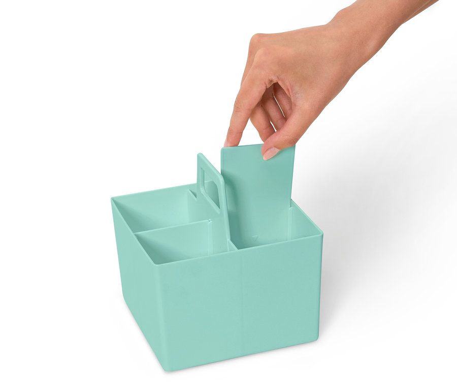 Une main insère une cloison dans un organisateur bleu clair avec plusieurs compartiments.