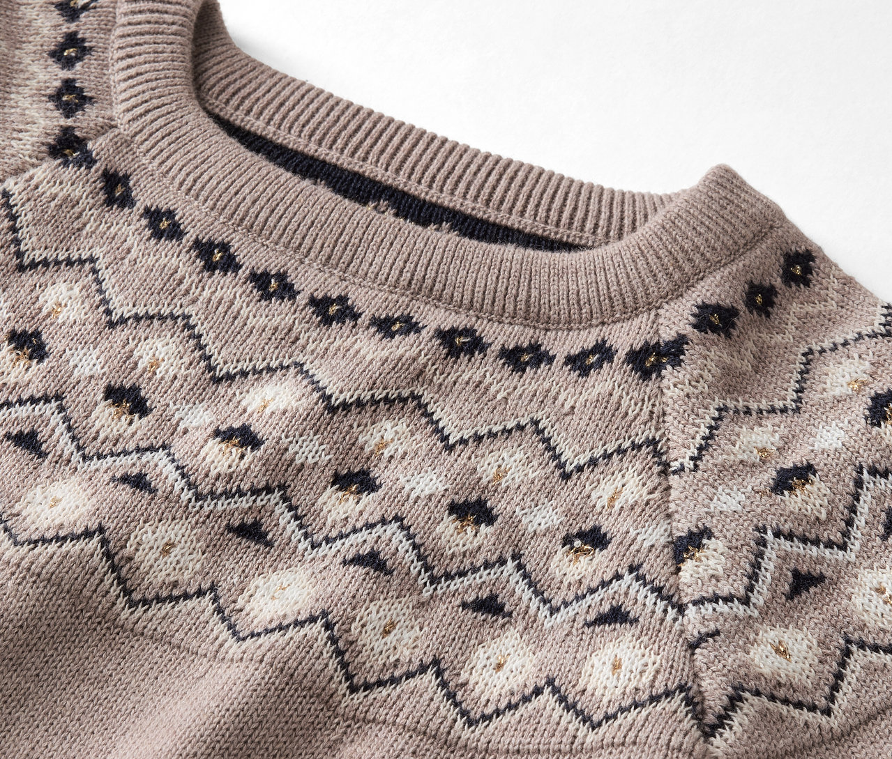 Gros plan d'un pull beige à motifs.