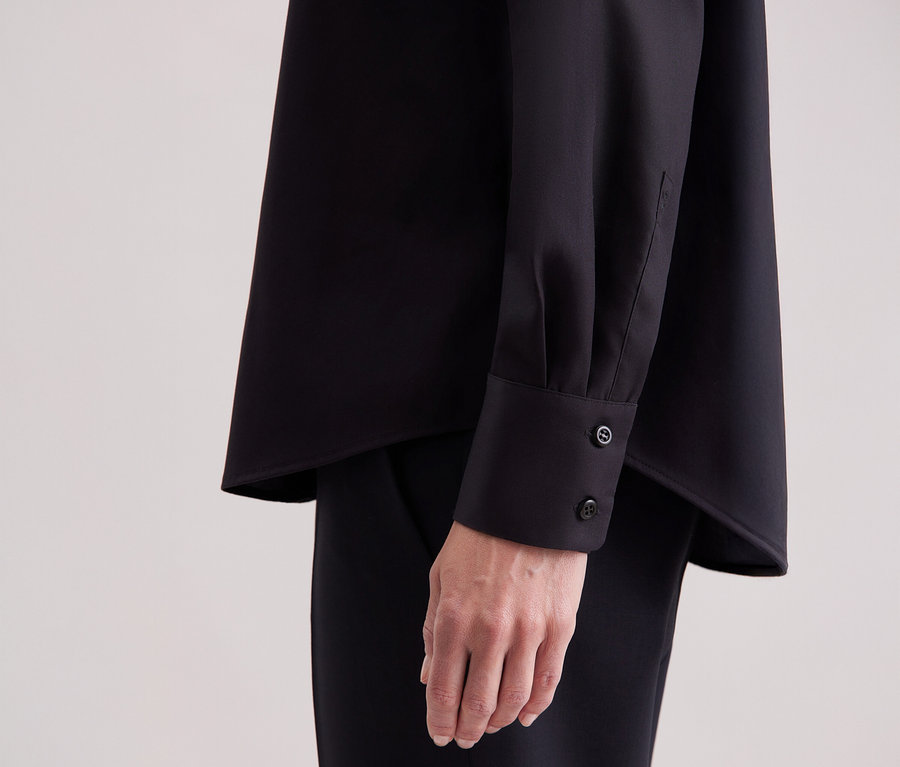 Gros plan d'une femme portant un chemisier noir Seidensticker de coupe régulière.