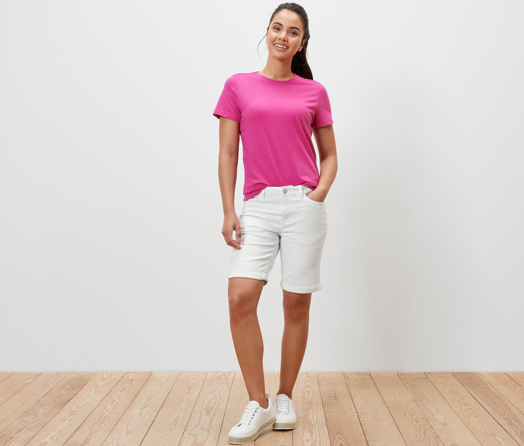 Une femme pose en short en jean blanc crème, coupe « Lea », et en t-shirt rose.