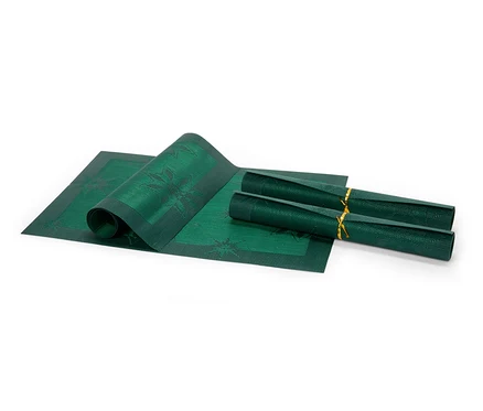 Un set de table vert à motifs est partiellement déroulé, à côté de lui se trouvent deux sets de table enroulés attachés par un ruban doré.