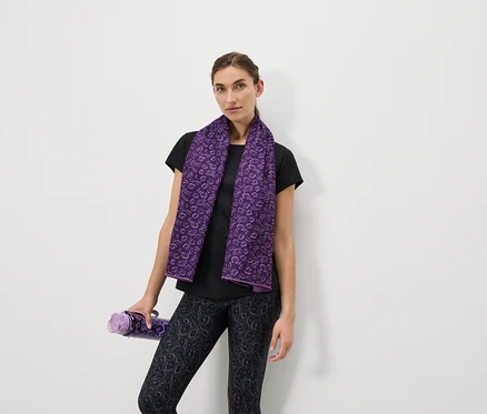 Femme avec une serviette violette autour du cou et une bouteille violette à la main.