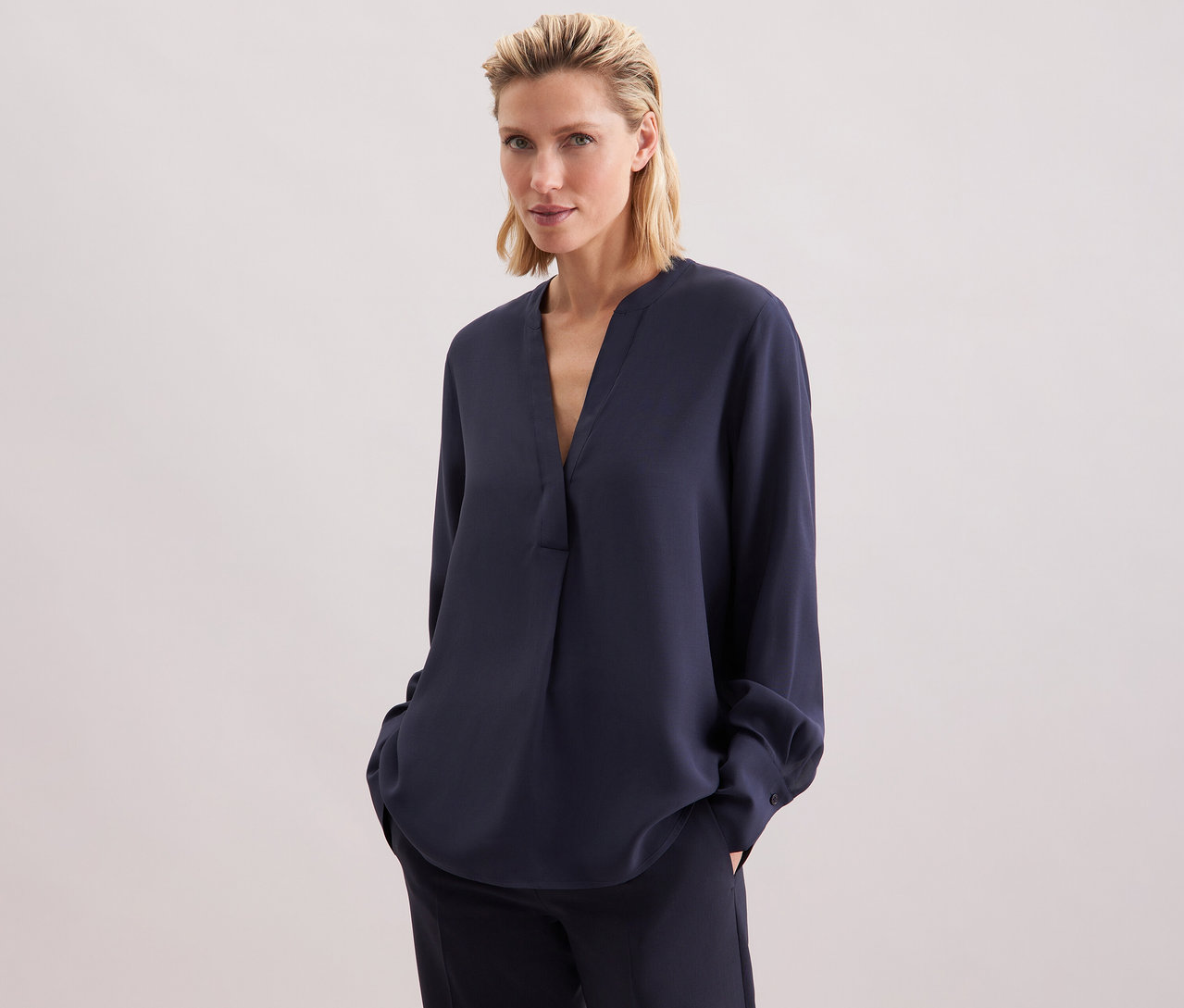 Femme portant une tunique en viscose Seidensticker bleu marine et un pantalon.