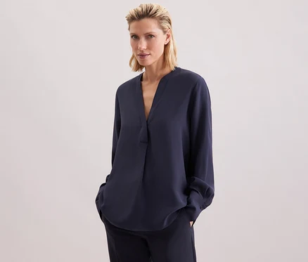 Femme portant une tunique en viscose Seidensticker bleu marine et un pantalon.
