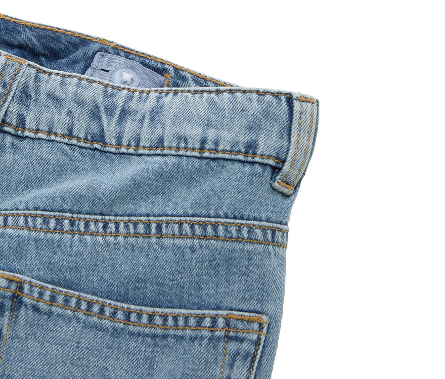 Détail d'un jean bleu avec taille ajustable et passant de ceinture.