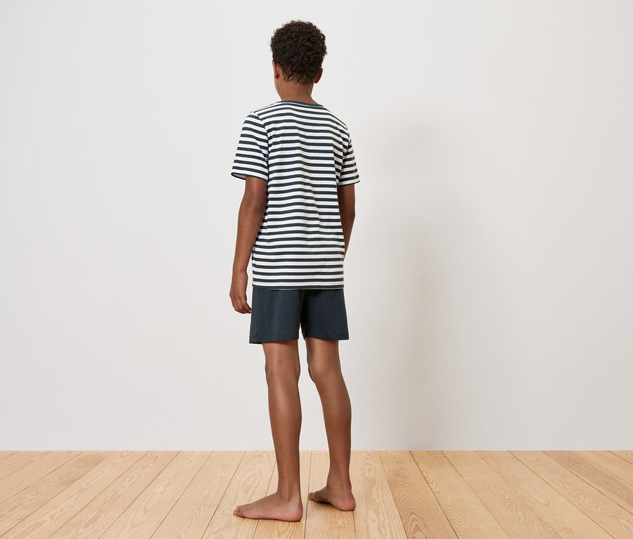 Garçon debout, dos tourné, portant un t-shirt rayé et un short.
