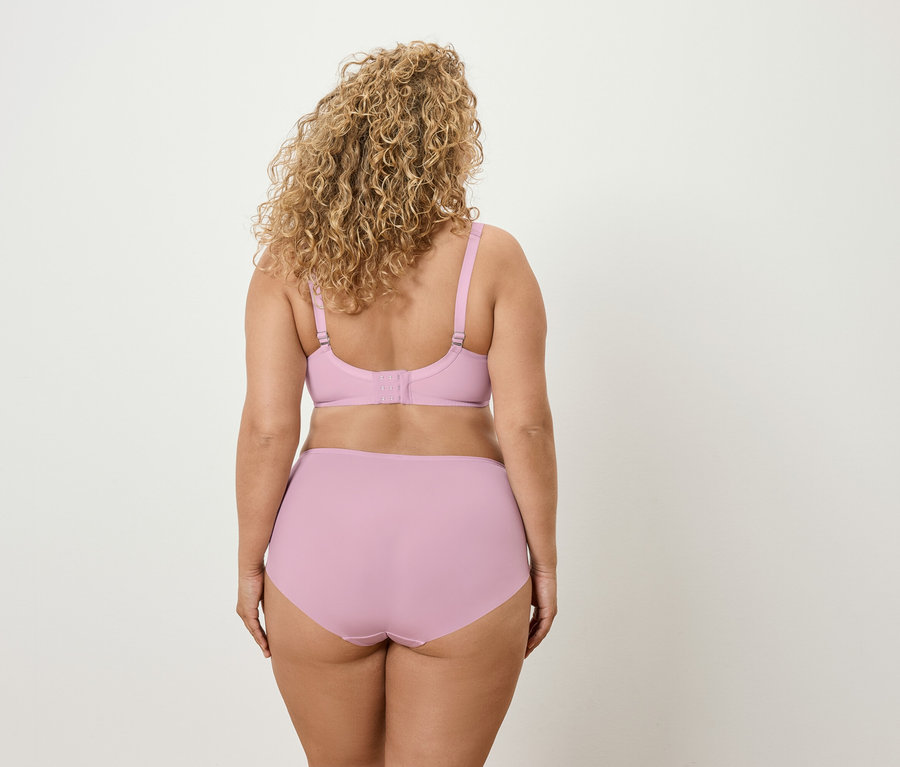 Vue de dos d'une femme aux cheveux bouclés portant un soutien-gorge et une culotte lilas clair.