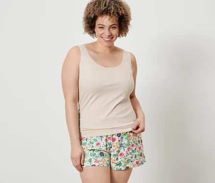 Une femme porte un débardeur couleur crème et un short à fleurs de l'ensemble 2 Shorts et 2 débardeurs.