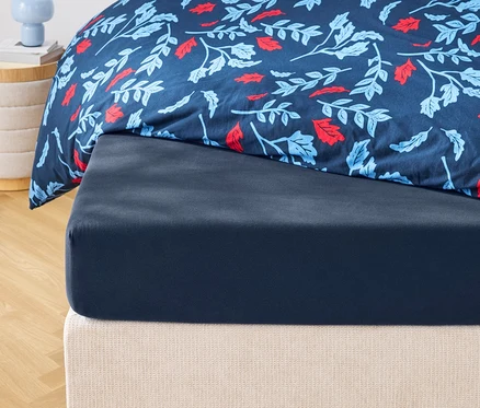 Gros plan d'un drap-housse bleu marine et d'une couette à motifs floraux.