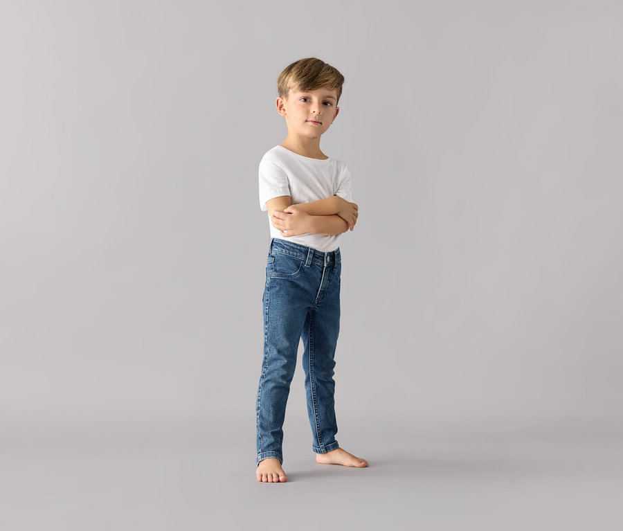 Un garçon se tient les bras croisés et porte un jean pour enfant – Fit « Jonas » et un t-shirt blanc.