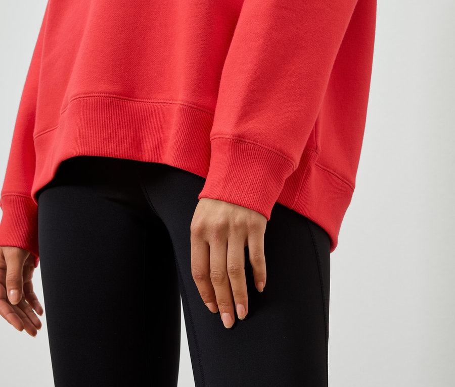 Gros plan d'une femme portant un sweat-shirt rouge et un legging noir.