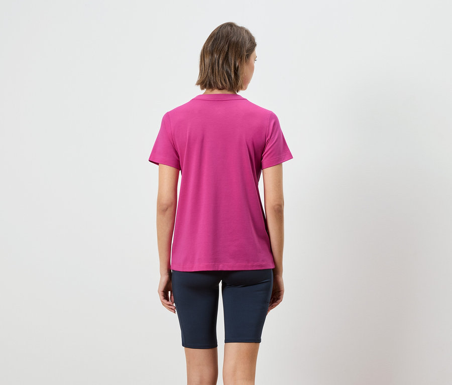 Vue arrière d'une femme aux cheveux bruns courts portant un polo rose et un legging court bleu marine.