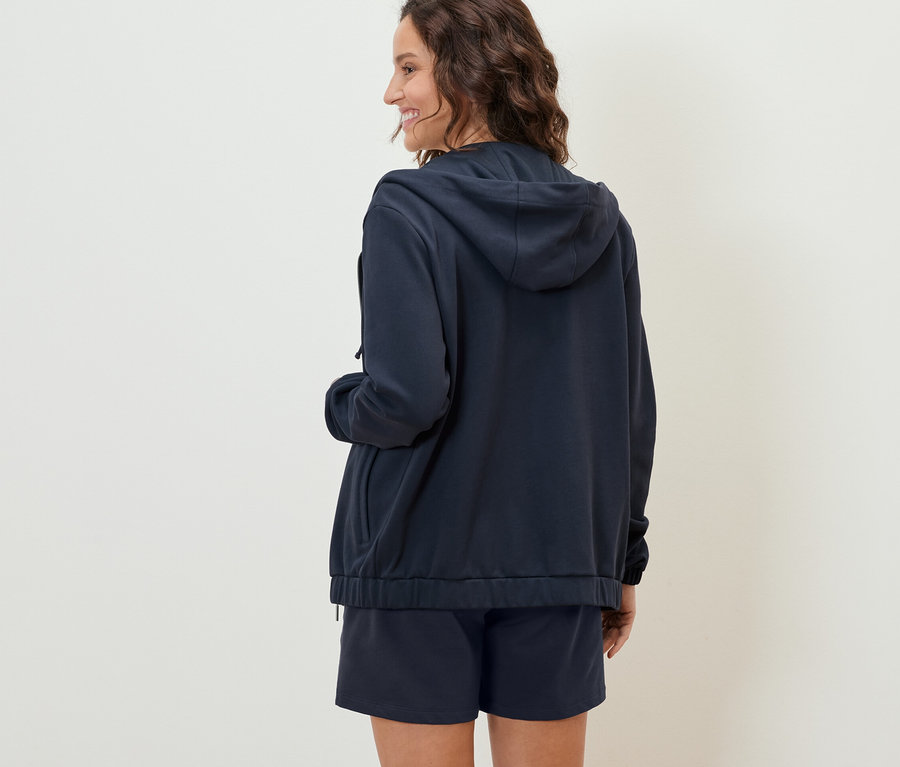 Femme vue de dos portant un sweat à capuche bleu foncé et un short.
