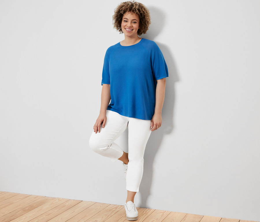 Femme posant en T-shirt en maille fine, bleu cobalt et pantalon stretch 7/8, blanc.