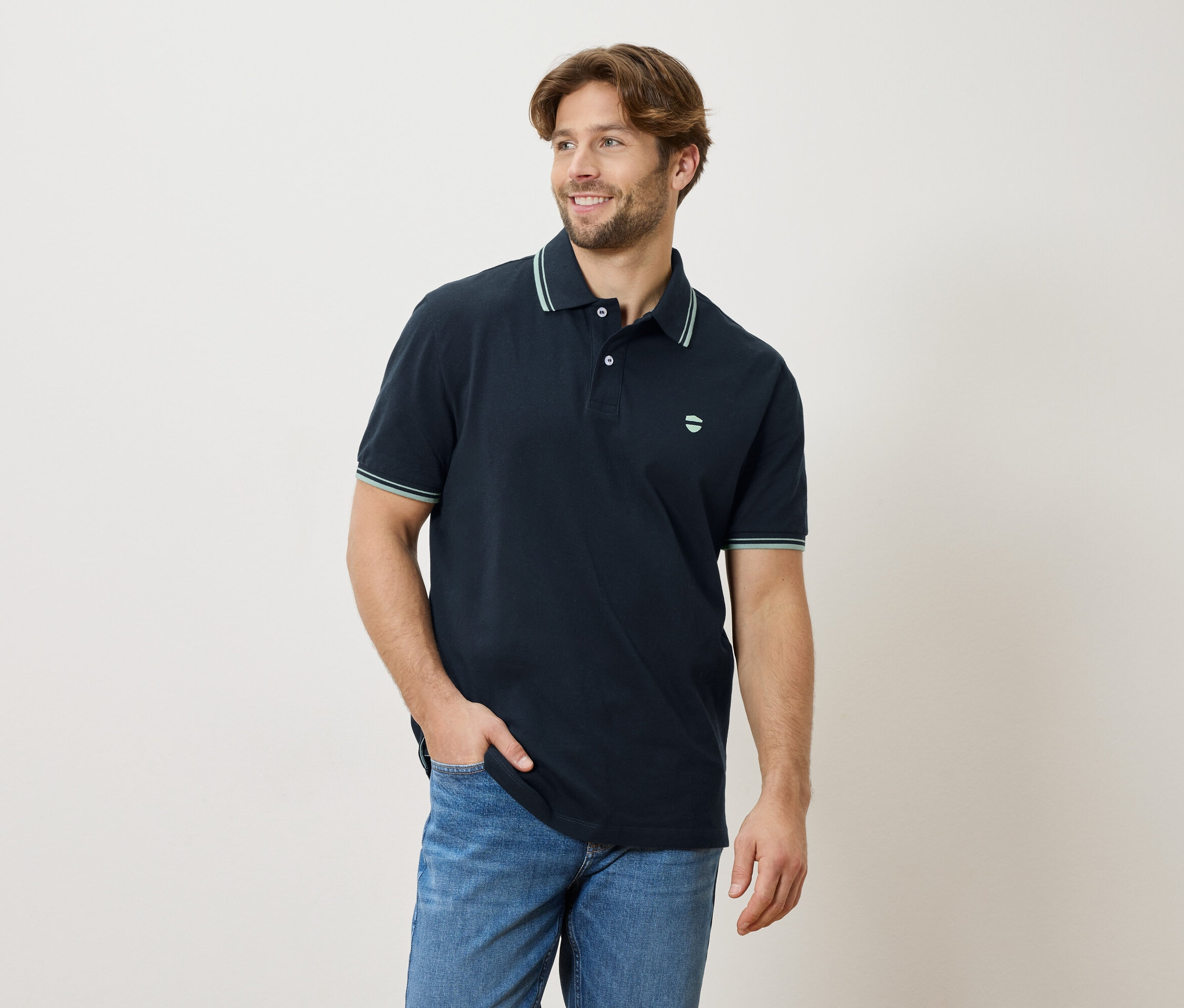 Homme portant un polo bleu marine et un jean