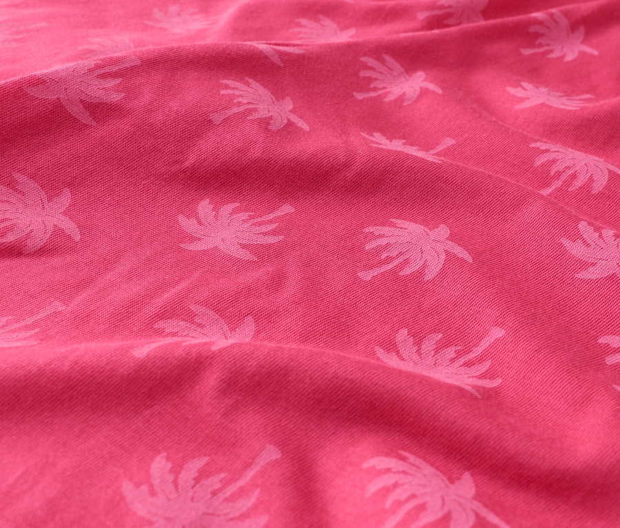 Gros plan d'un tissu rose avec un motif de palmiers.