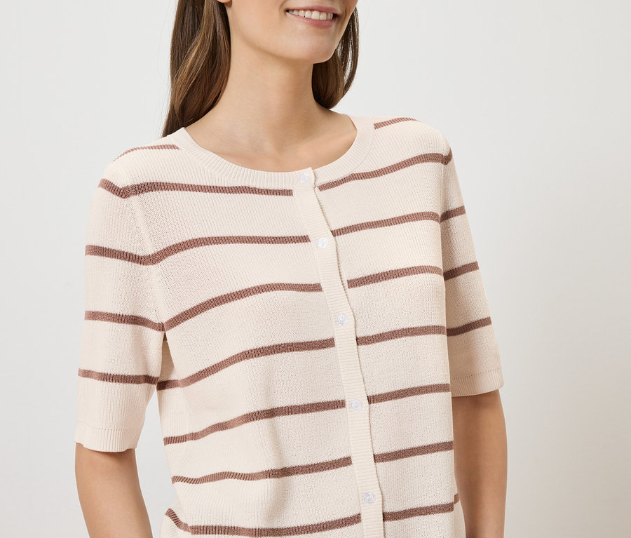 Femme portant un cardigan beige rayé à manches courtes avec des boutons.