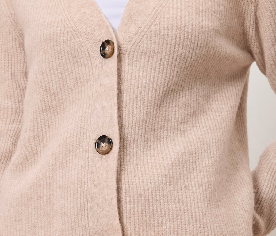 Gros plan sur un cardigan tricoté rose clair avec deux boutons et un col en V.
