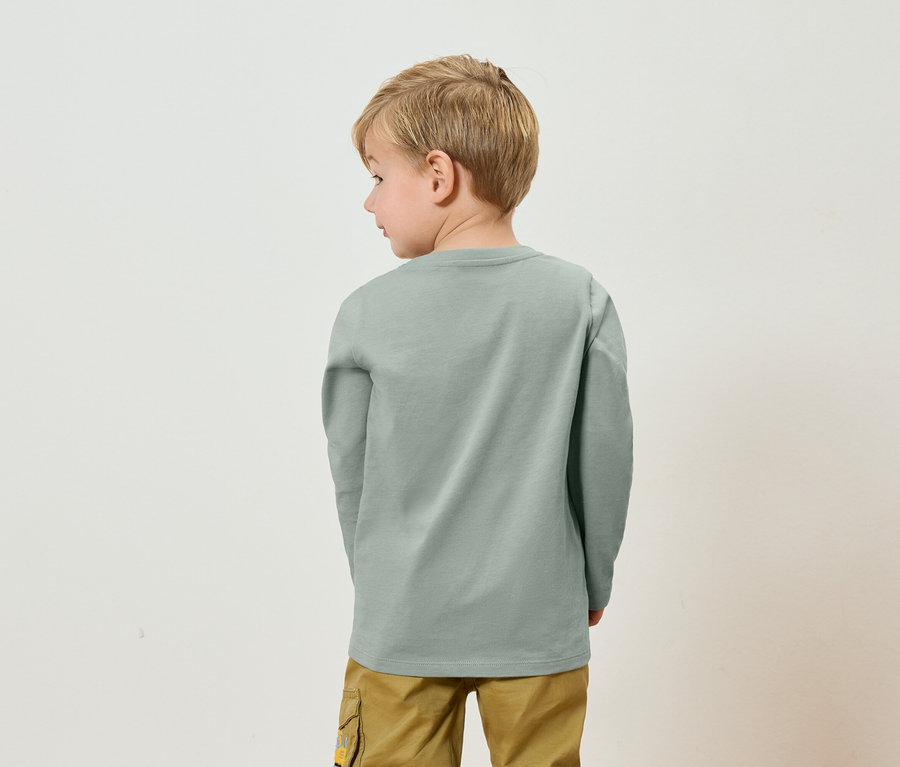 Vue arrière d'un enfant blond portant un t-shirt à manches longues gris et un pantalon kaki.
