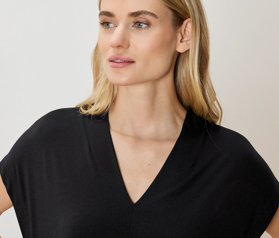 Femme portant un haut noir à col en V.