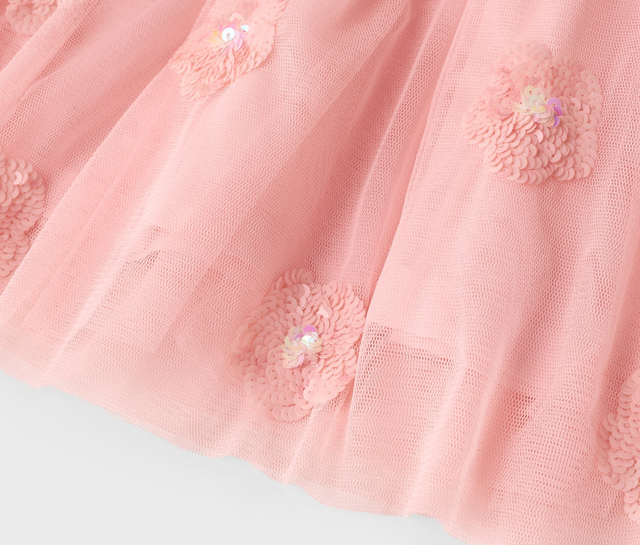 Gros plan d'une jupe en tulle rose avec des applications de fleurs à paillettes.
