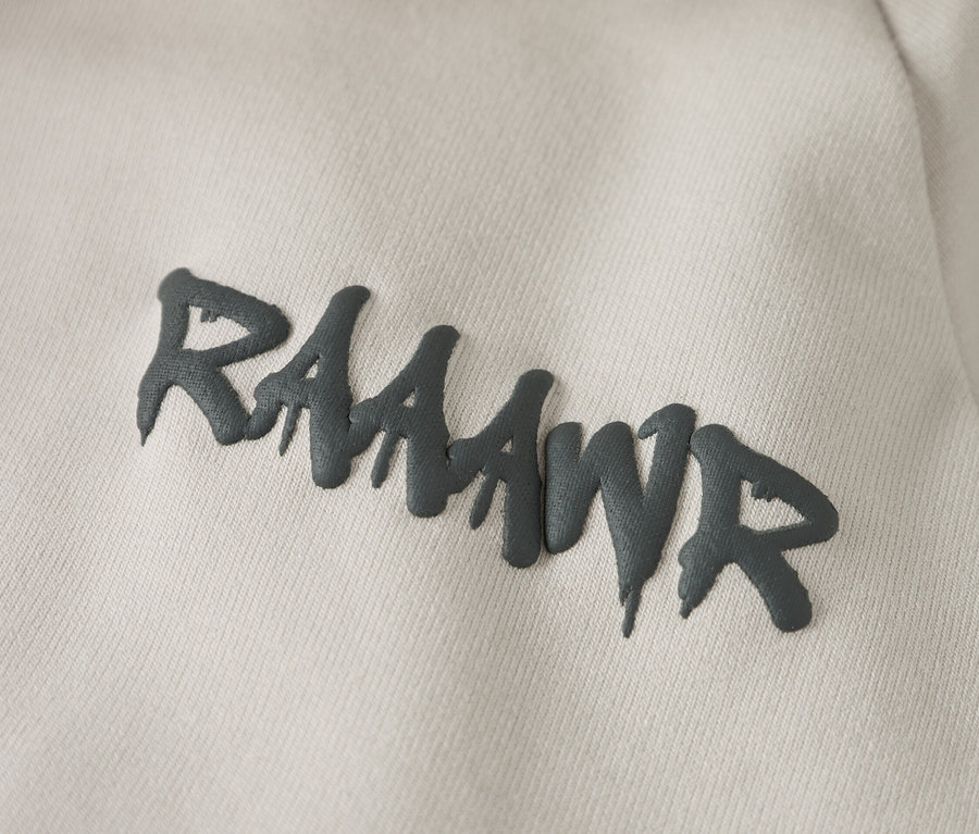 Gros plan sur un sweat à capuche beige clair avec l'inscription grise "RAAAWR".