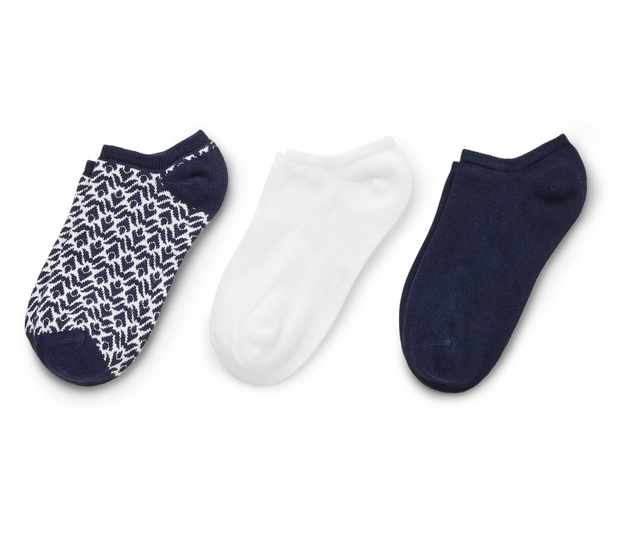 Trois chaussettes sont posées sur un fond blanc. Une chaussette est blanche, une est bleu marine et une est bleu marine avec un motif blanc.
