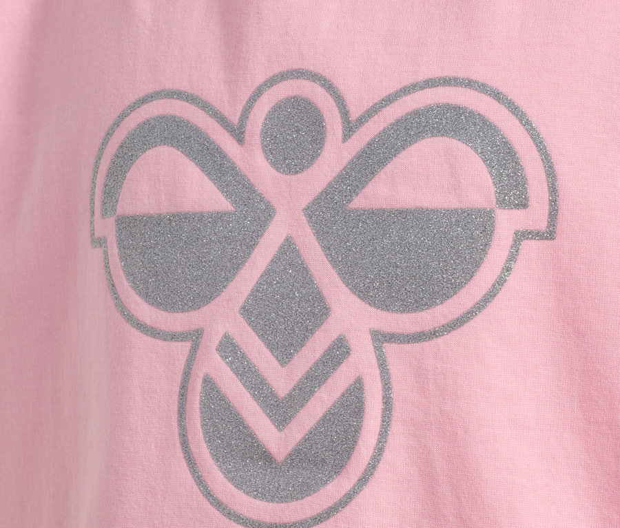 Gros plan d'un t-shirt rose avec un logo Hummel argenté.
