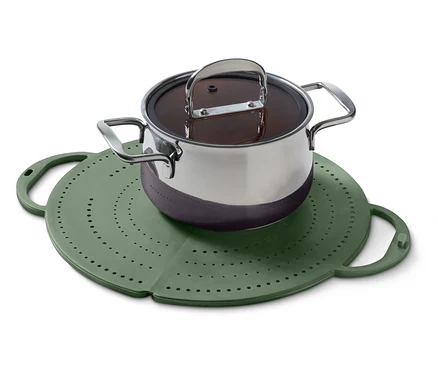 Une casserole avec couvercle est posée sur un cuiseur vapeur en silicone vert et rond.