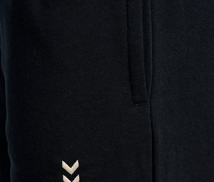Gros plan d'un pantalon de jogging noir avec une poche latérale et un logo Hummel brodé.