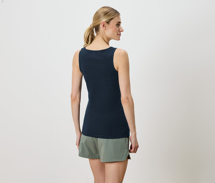 Femme portant un haut bleu marine sans manches et un short vert, vue de dos.