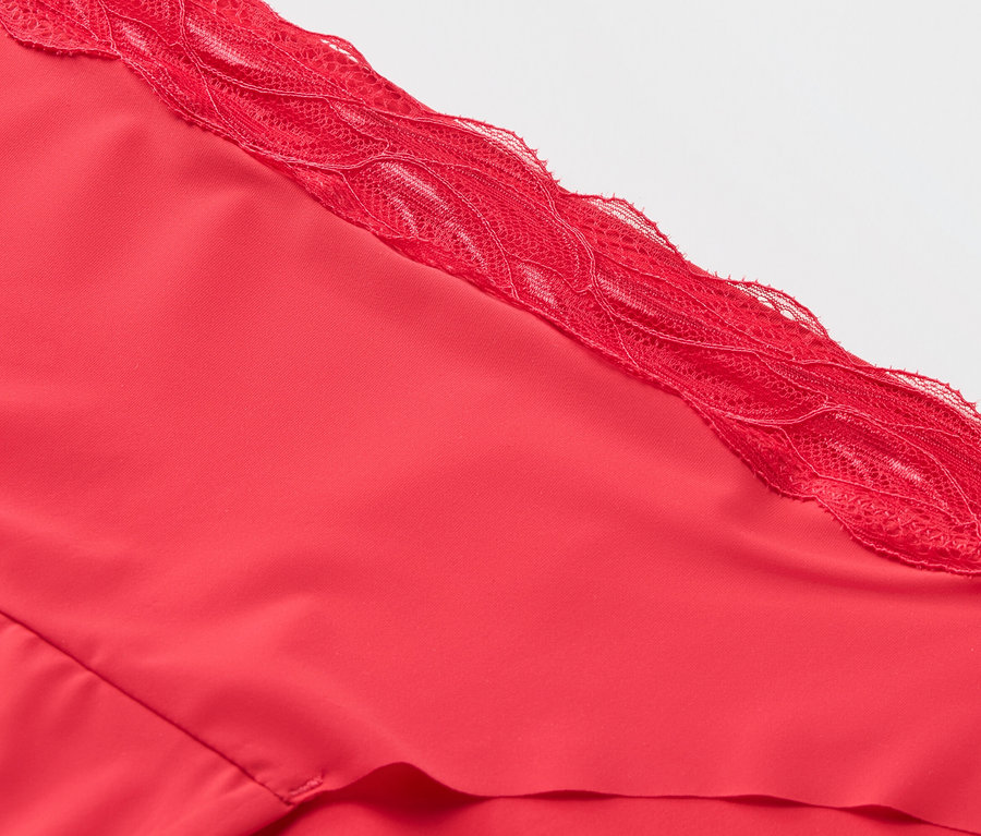 Gros plan sur un haut en tissu rouge avec des finitions en dentelle.
