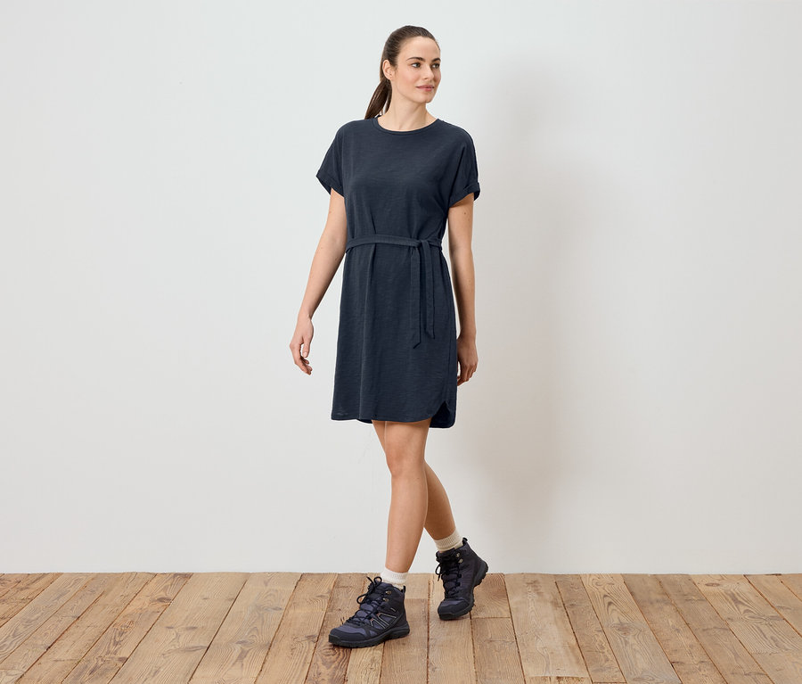 Femme portant une robe t-shirt bleue avec une ceinture et des chaussures de randonnée.